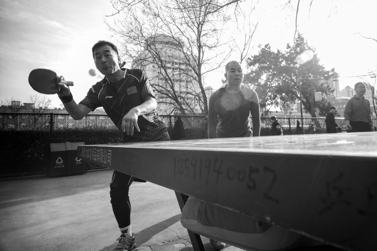 services-04 Dynamic black and white photo capturing an outdoor ping pong game with two players.