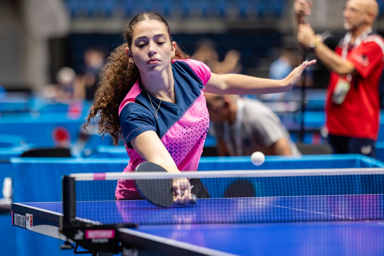 about-us A female athlete intensely focused during a competitive table tennis match, showcasing skill and determination.