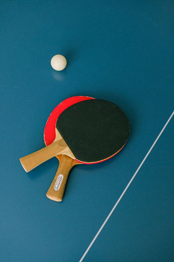 services-01 Flat lay of ping pong paddles and ball on a table tennis surface.